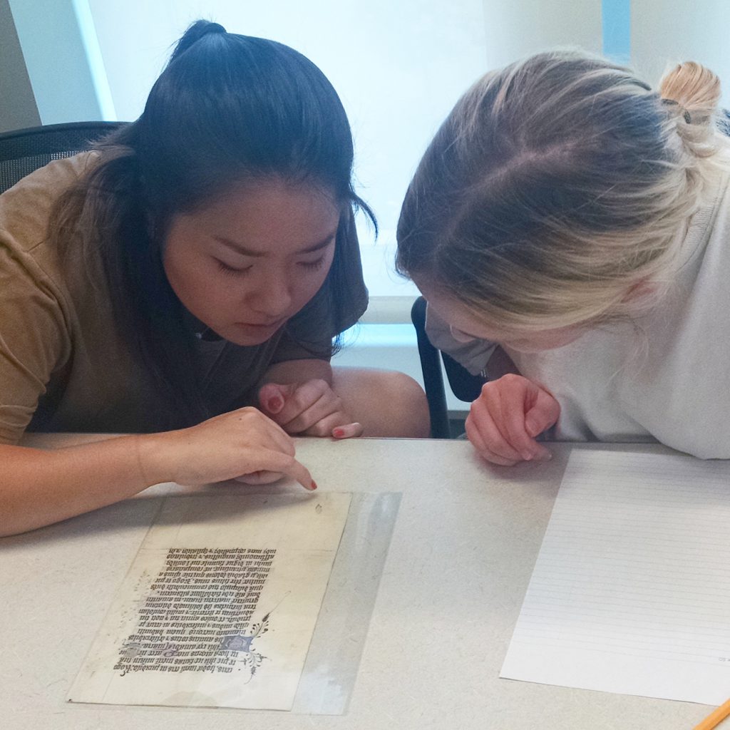 Two students pour over a fragment