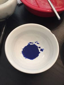A picture of a bowl of ultramarine powder mixed with egg yolk. It is a very opaque, rich blue color.