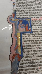 An image of an illuminated initial with an arrow pointing to the pink section of it