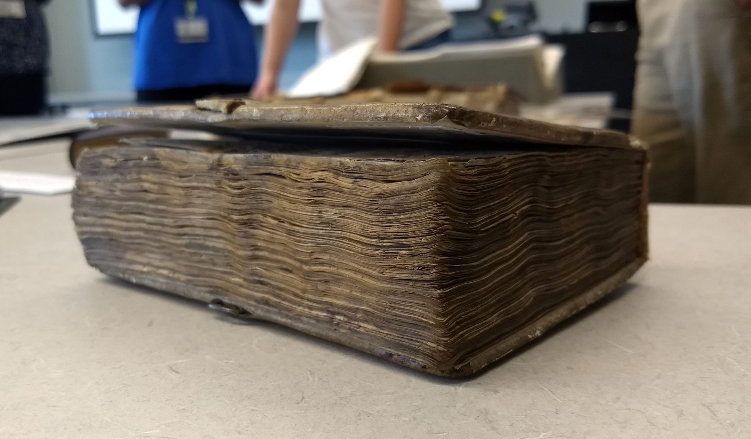The fore edge of a very old book, lying on a table.
