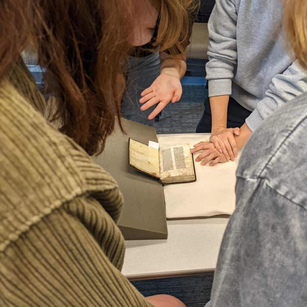 students gather around a small, open book