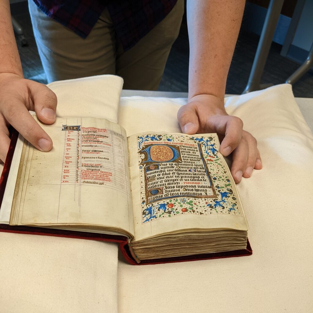 A highly decorated manuscript being held open.