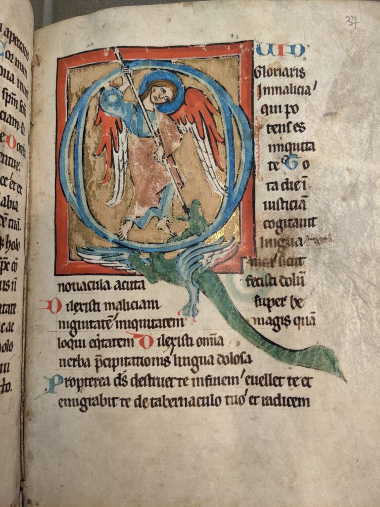 An angel with a spear stabs a dragon in a medieval manuscript page