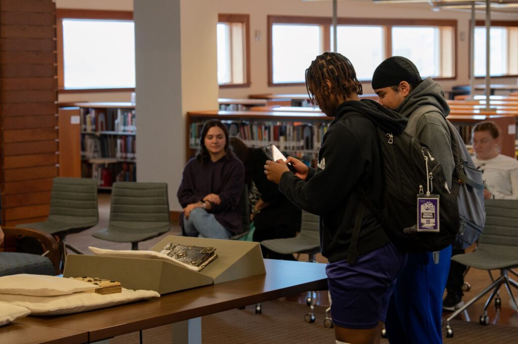 Students stand around a book with metal on its cover