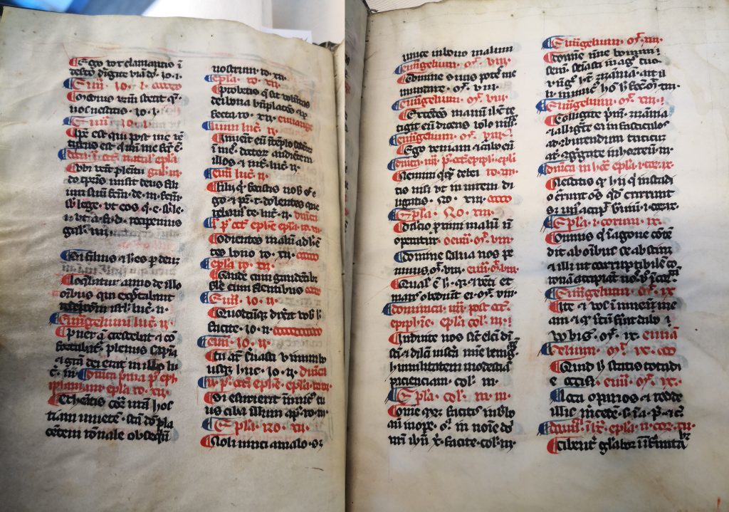 Two side-by-side photographs of two pages from the table of contents. Each page has two columns of text written in black and red ink and alternating blue and red pilcrows.