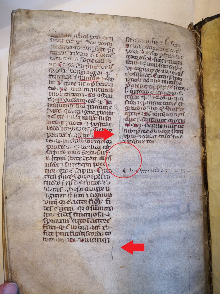 A photograph of the verso of folio 136. This is the last page of the book. It shows half of the second column of the text is erased. Arrows point to the remnants of the initial and a circle indicated where the initial would have appeared on the page.