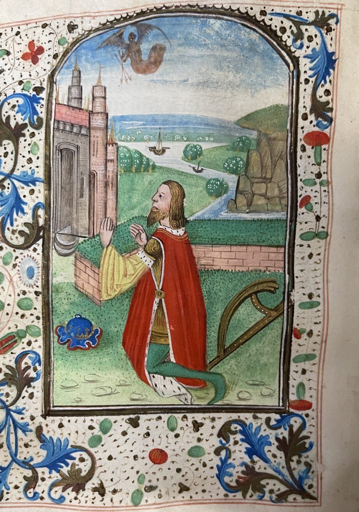 Full-page miniature of King David in a posture of prayer. He is outside in front of a river and a castle. A translucent brown being holding three arrows hovers above the landscape.
