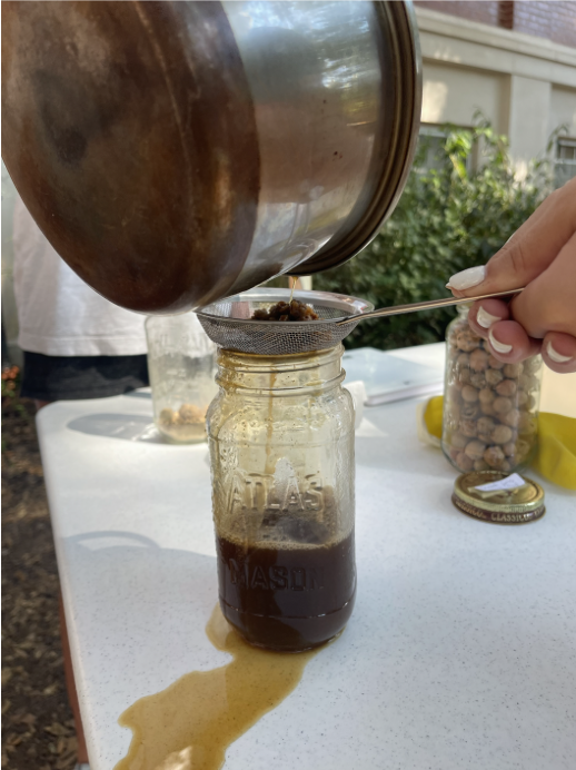 Pouring oak gall mixture through strainer into jar.
