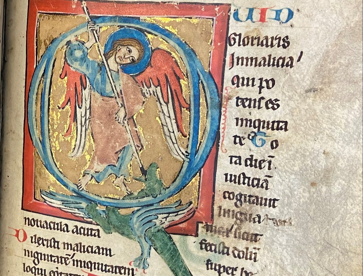 A parchment page with lines of Psalm verses in Latin gothic script and a large, historiated 'Q' initial featuring St. Michael slaying a dragon in the top right corner.