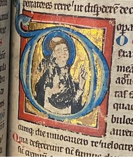 Medieval initial showing Saint Dominic. The saint's hand and robe have been damaged, but his face remains intact. 