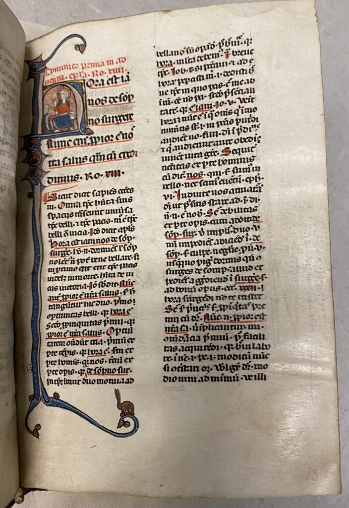 Manuscript page with historiated initial, text, and a bunny on a lower border flourish
