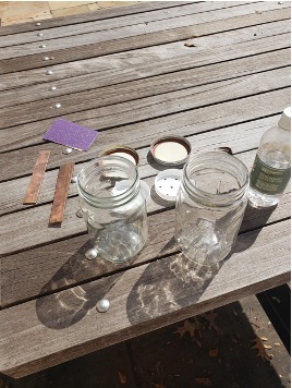 Jars, lids, vinegar, sand paper, and copper strips on a table