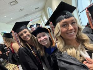 Meredith Wessel, Jennifer Gay, and Madeline Kerestman in cap and gown at commencement.